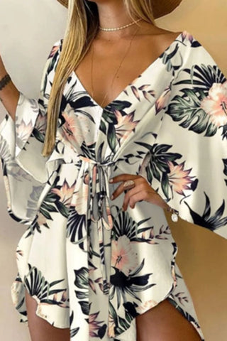 Chic floral-printed romper with plunging neckline and cold-shoulder sleeves. Stylish tropical-inspired attire for fashionable women.