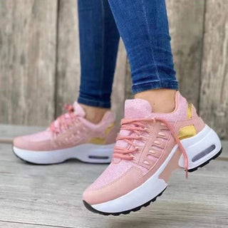 Fashionable pink women's athletic sneakers with yellow accents, displayed on a wooden surface.