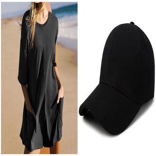 Casual women's black jumpsuit with pockets and a black baseball cap on a beach setting.