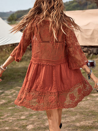 Rust-colored boho dress with lace details and flowing sleeves, worn by a woman with wavy brown hair in an outdoor setting.