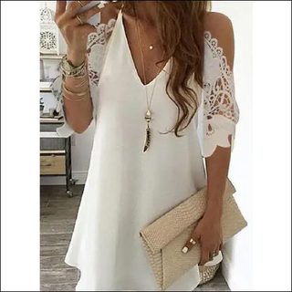 Elegant white dress with lace sleeves, adorned with necklace and bracelets, showcasing a fashionable and stylish look.