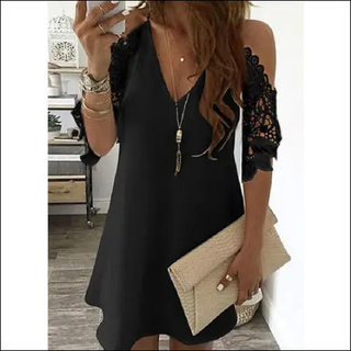 Elegant black dress with lace sleeves, bohemian jewelry, and beige tote bag.