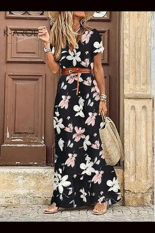 Elegant floral print dress with V-neck, cinched waist, and full skirt. Stylish straw bag completes the casual yet fashionable look. Placed in front of a traditional wooden door.