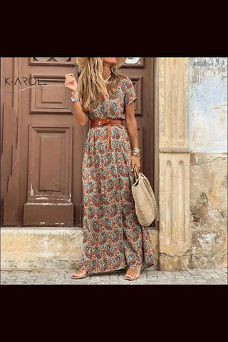 Elegant floral maxi dress on display in K-AROLE store. The dress features a vibrant, colorful floral print pattern and a flowing, ankle-length silhouette. The model showcases the dress's stylish, feminine design and versatility for various occasions.