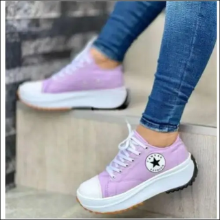 Purple lace-up casual sneakers with thick soles on a woman's feet.