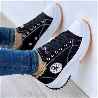 Black and white canvas sneakers with thick soles and a Converse logo, worn with blue jeans.