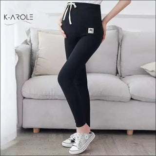 Comfortable black maternity leggings with drawstring detail, worn with casual sneakers, showcased in a cozy indoor setting.
